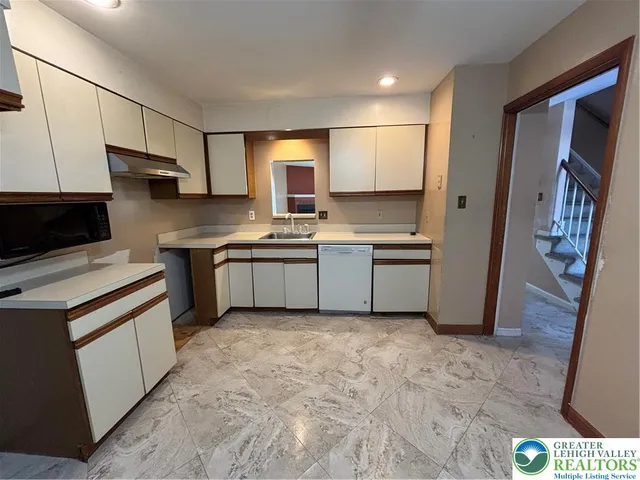 a kitchen with stainless steel appliances a sink a stove a refrigerator cabinets and a window