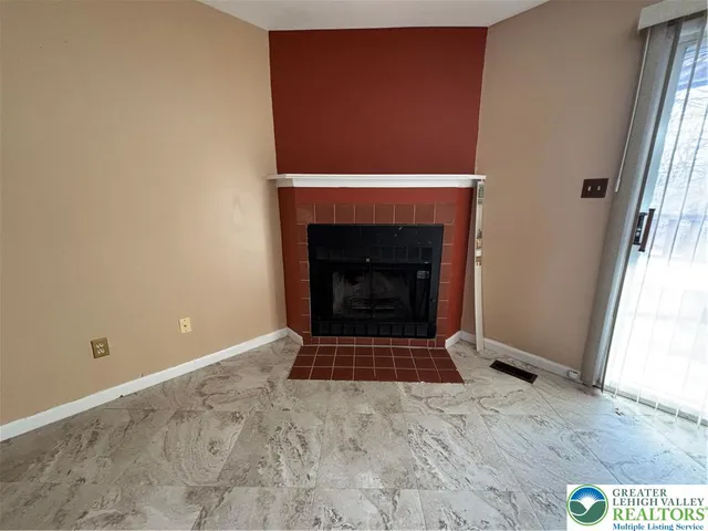 a view of an empty room with wooden floor and a fireplace