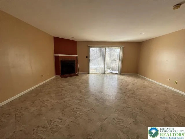 an empty room with windows and fireplace