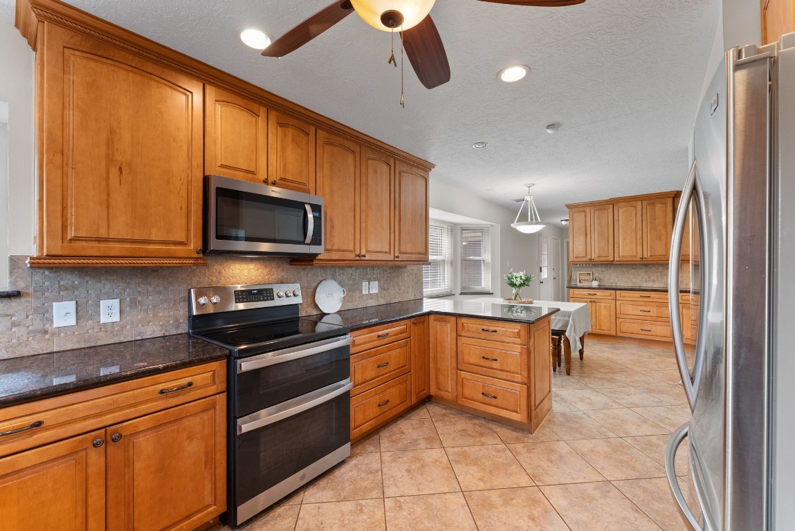 16927 Windypine Drive Spring, TX 77379 - Photo 11 of 46 a kitchen with stainless steel appliances granite countertop wooden cabinets a stove top oven a sink and dishwasher