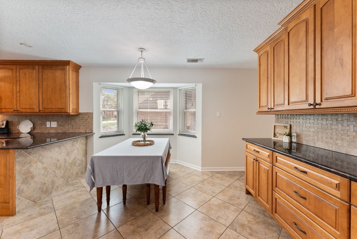 16927 Windypine Drive Spring, TX 77379 - Photo 12 of 46 a kitchen with granite countertop a sink a stove a dining table and chairs
