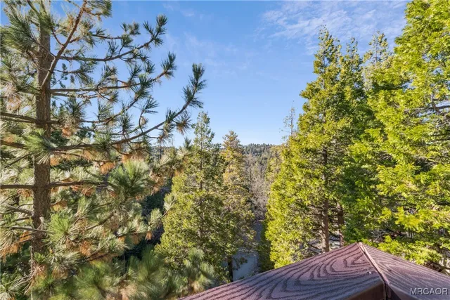 a view of a house with a wooden bench next to a yard