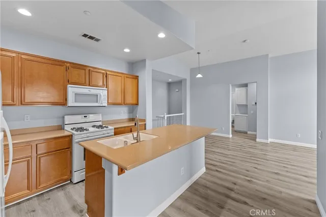 a large kitchen with stainless steel appliances granite countertop a sink dishwasher a stove and a refrigerator with wooden cabinets