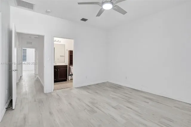 an empty room with wooden floor and ceiling fan