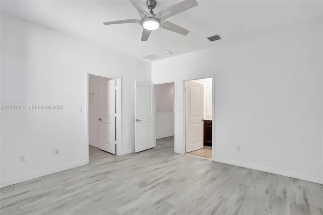 an empty room with wooden floor fan and windows