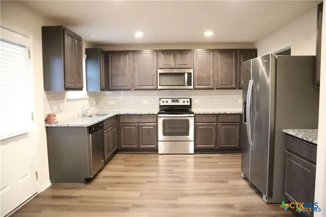 a kitchen with stainless steel appliances granite countertop a refrigerator and a stove top oven