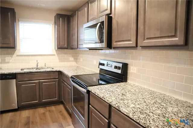 a kitchen with stainless steel appliances granite countertop a sink stove and microwave