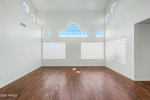an empty room with wooden floor exposed radiator and windows