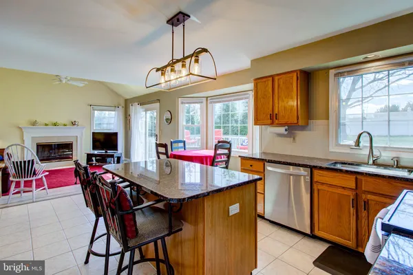 a room with stainless steel appliances granite countertop a kitchen island a stove and a view of living room