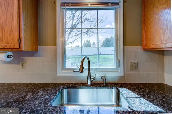 a kitchen with granite countertop a sink a window and cabinets