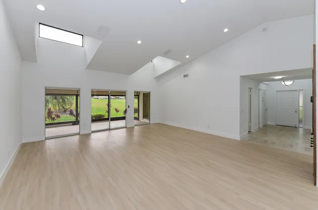 a view of an empty room with window and wooden floor