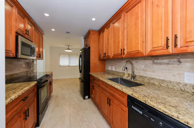 a kitchen with granite countertop a sink a stove and cabinets