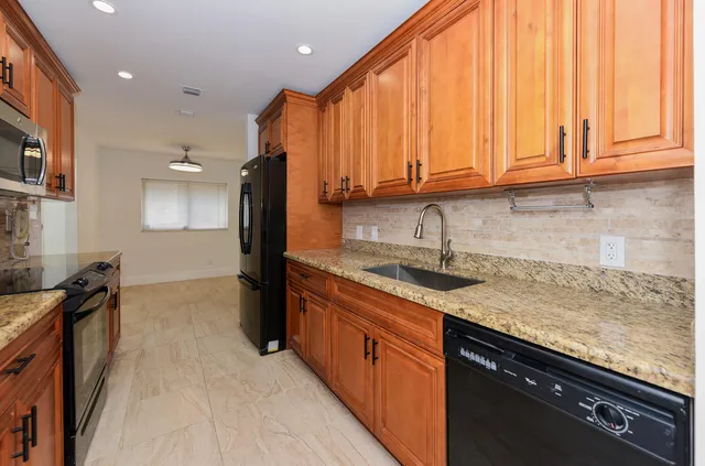 a kitchen with granite countertop a sink a stove and a wooden cabinets