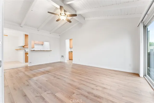 an empty room with wooden floor fan and windows