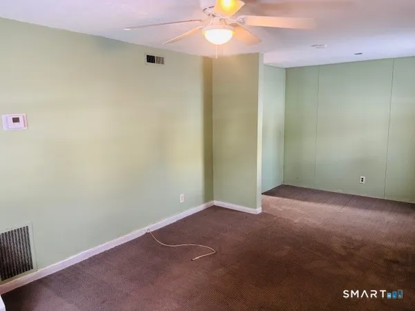 an empty room with a fan and chandelier fan