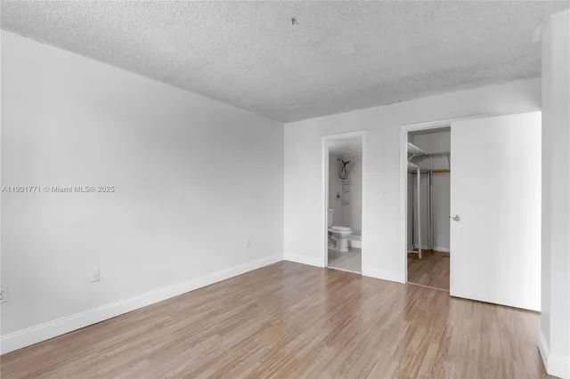 a view of an empty room with wooden floor and closet
