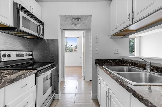 a kitchen with granite countertop a sink stove and cabinets