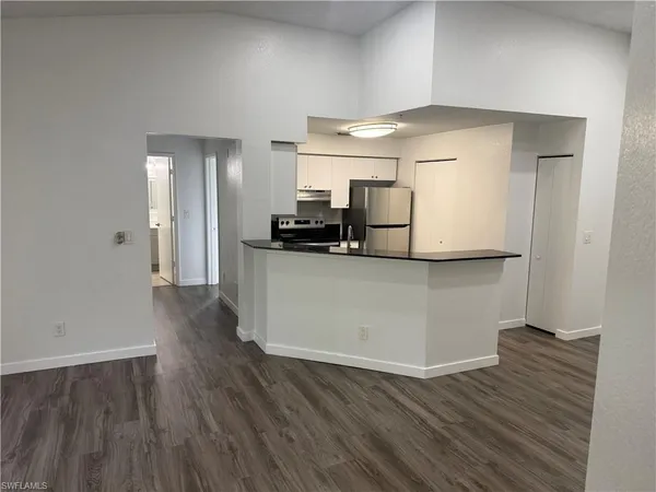 a view of a kitchen with wooden floor and electronic appliances