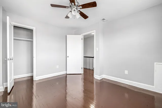 an empty room with wooden floor closet and windows