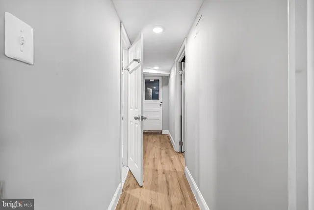 a view of a hallway with wooden floor and a bathroom