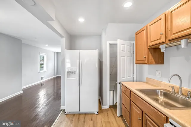 a kitchen with a sink a refrigerator and wooden floor