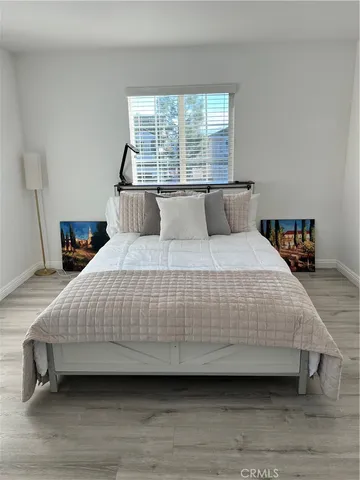 a bedroom with a bed a window and a potted plant on table
