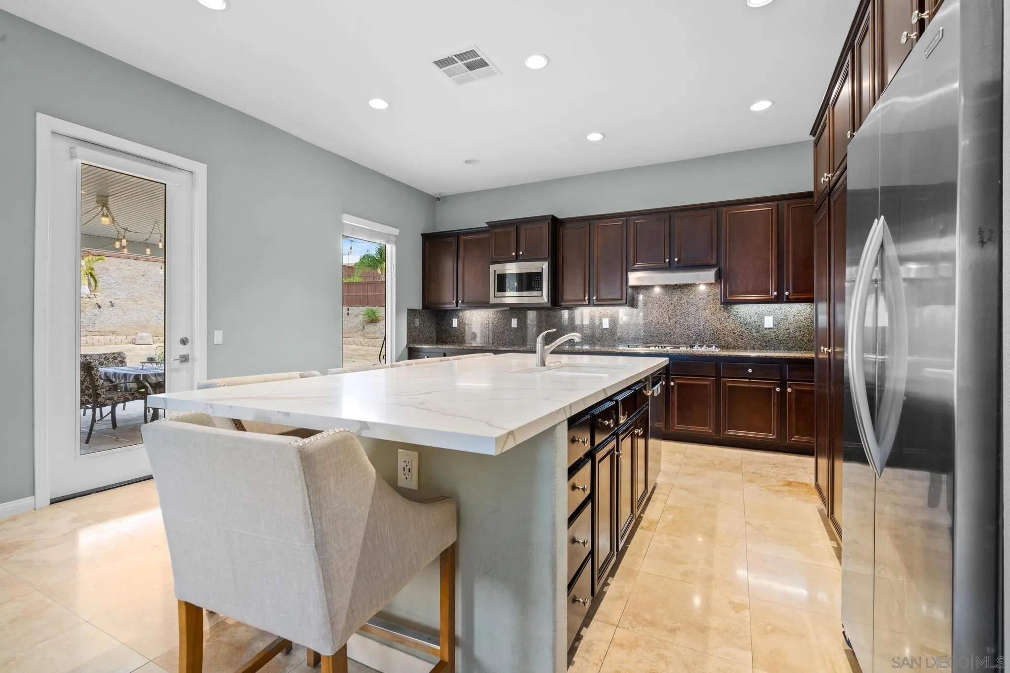 3252 Hidden Estates Lane Escondido, CA 92027 - Photo 8 of 32 a kitchen with stainless steel appliances granite countertop a table chairs sink refrigerator and microwave