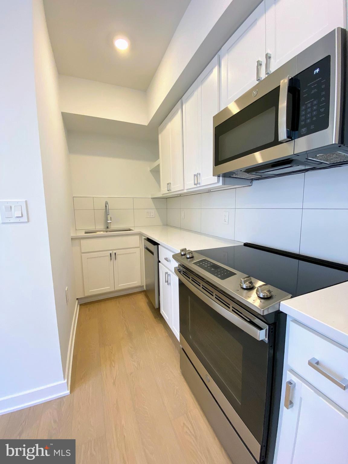 3435 Brown Street Northwest, Unit 1 Washington, DC 20010 - Photo 1 of 13 a kitchen with stainless steel appliances a stove a microwave and white cabinets