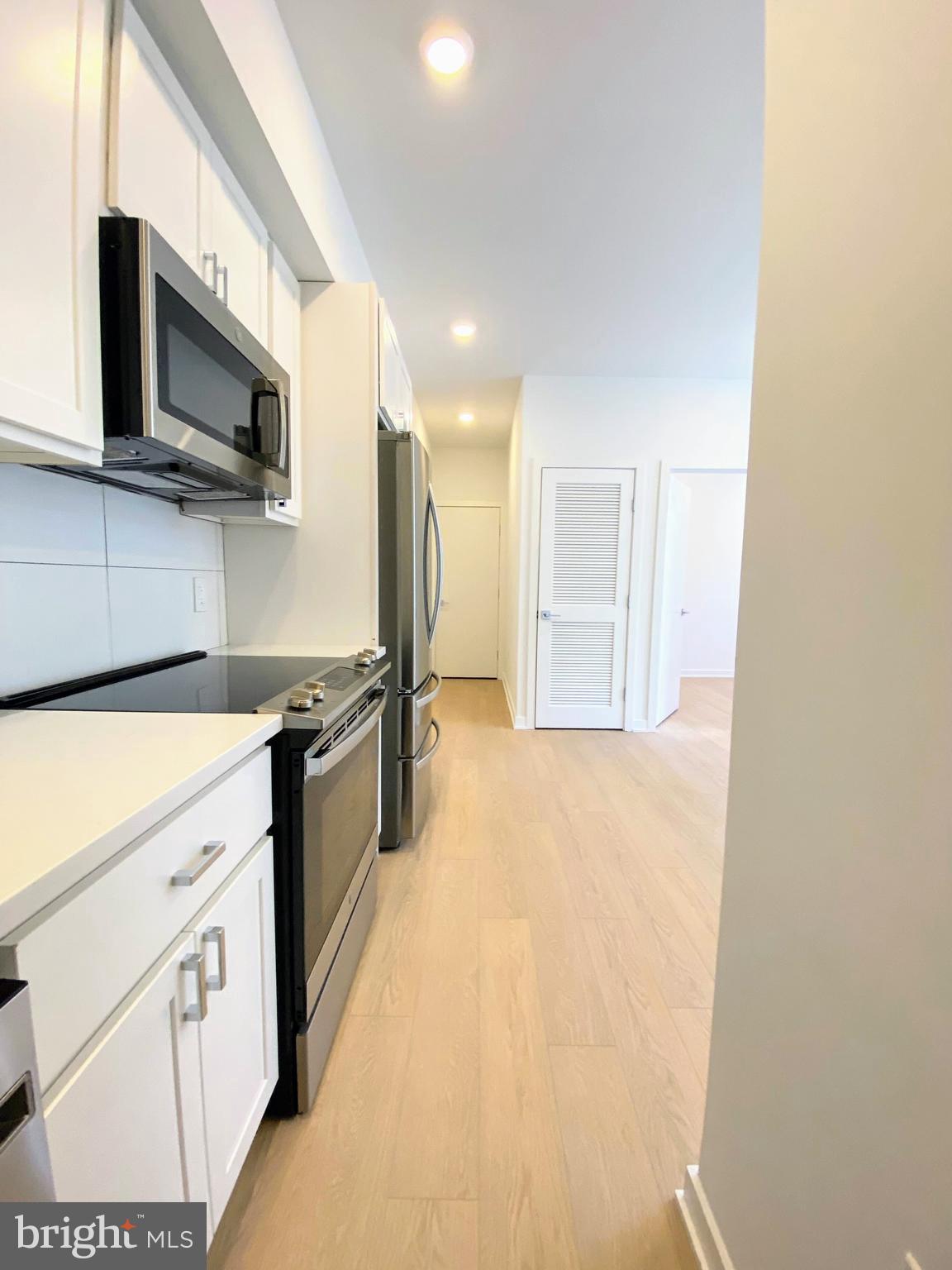 3435 Brown Street Northwest, Unit 1 Washington, DC 20010 - Photo 2 of 13 a large kitchen with stainless steel appliances a stove a microwave and white cabinets