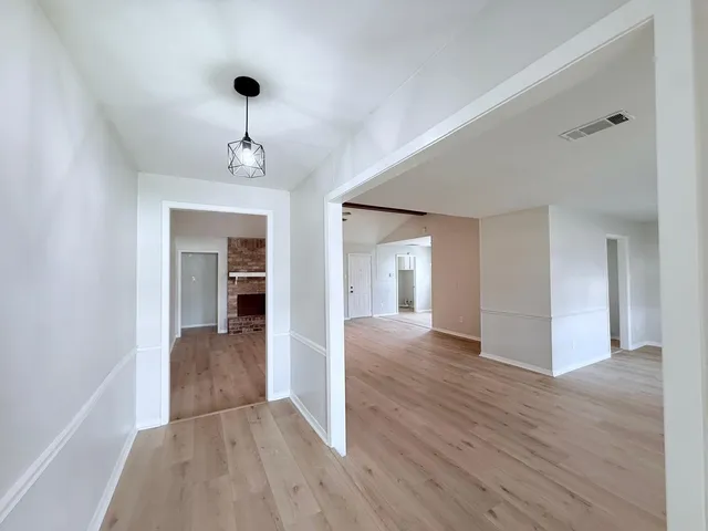 a view of a hallway with wooden floor and a living room