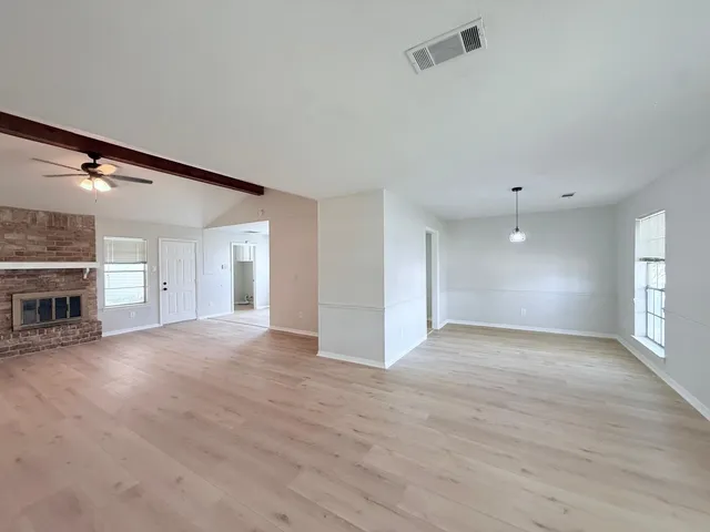 an empty room with wooden floor and fireplace