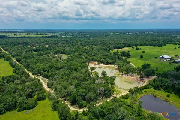 an aerial view of residential houses with outdoor space and trees