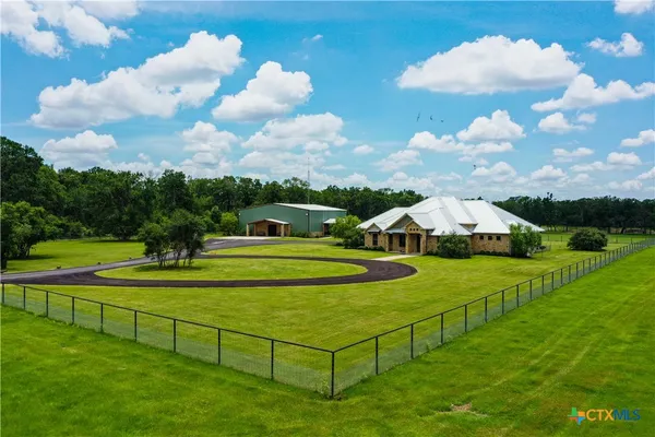 a view of a white house with a big yard and a fountain
