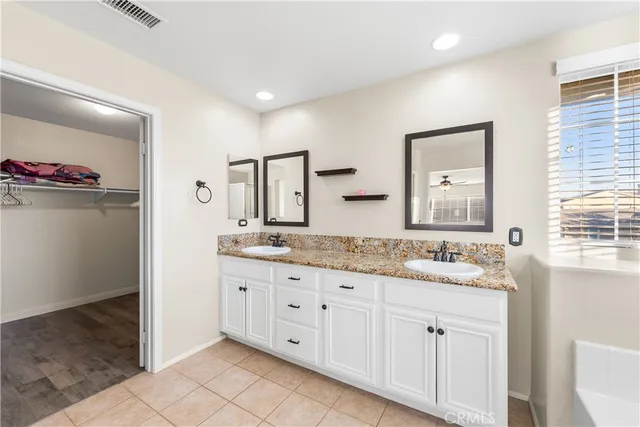a bathroom with a granite countertop double vanity sink and a mirror