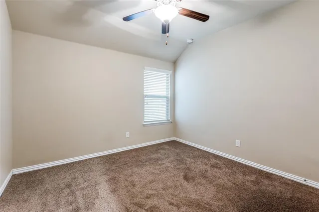an empty room with a chandelier fan and windows