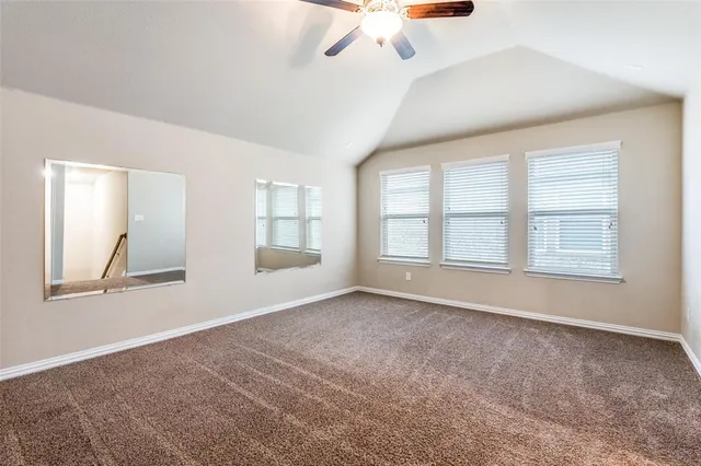 an empty room with chandelier fan and windows