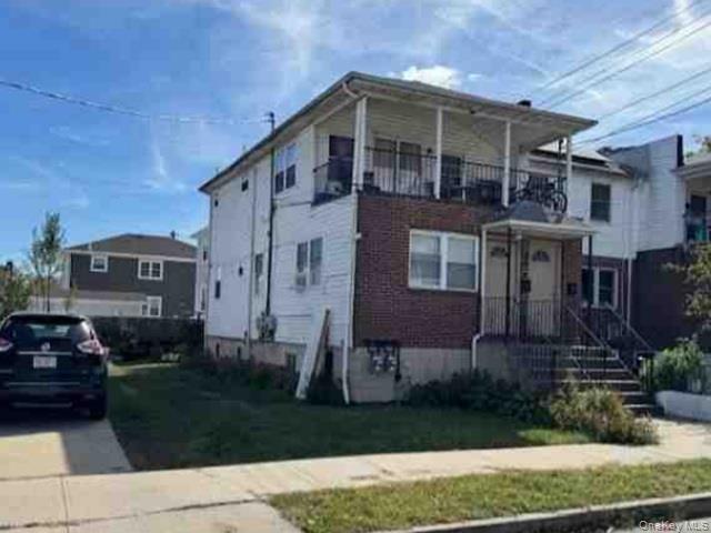 View of front of home featuring a front lawn and a balcony