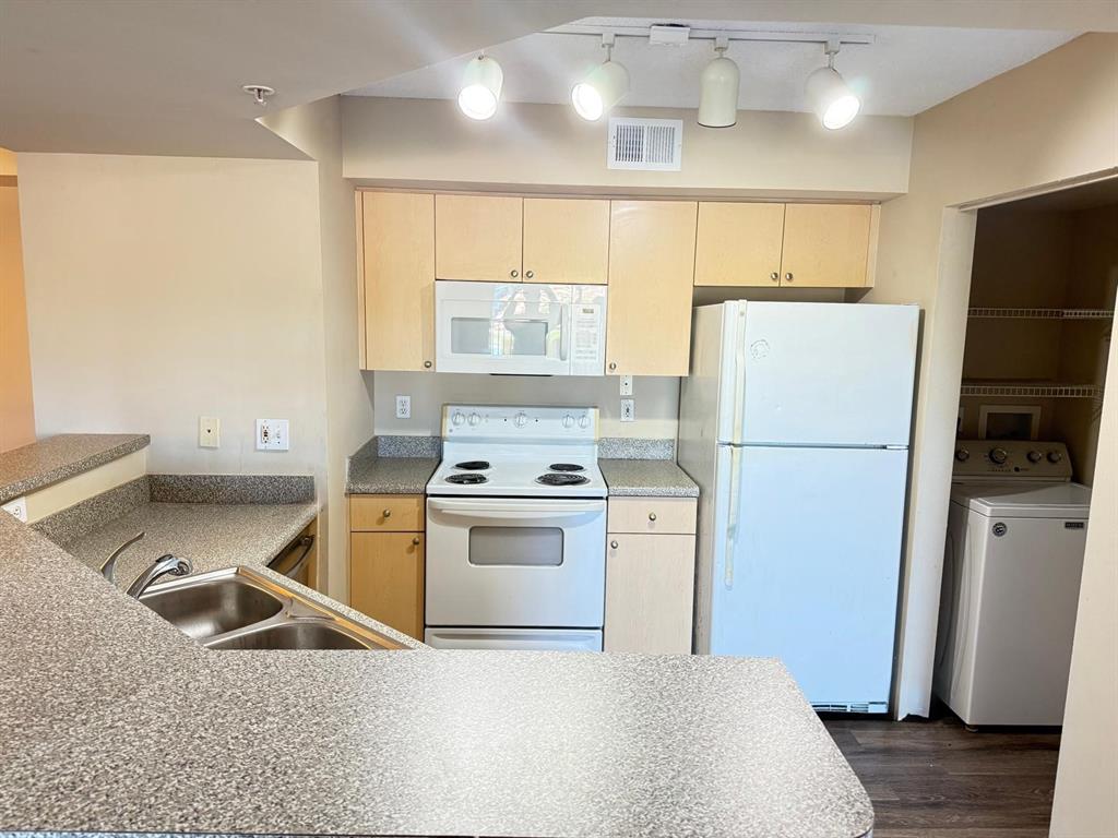 3779 Northwest Mediterranean Lane, Unit 207 Jensen Beach, FL 34957 - Photo 11 of 20 a kitchen with a refrigerator sink stove and wooden floor