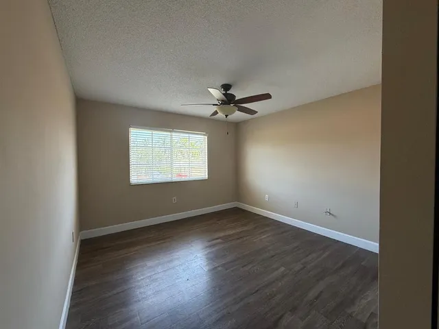 an empty room with wooden floor and ceiling fan
