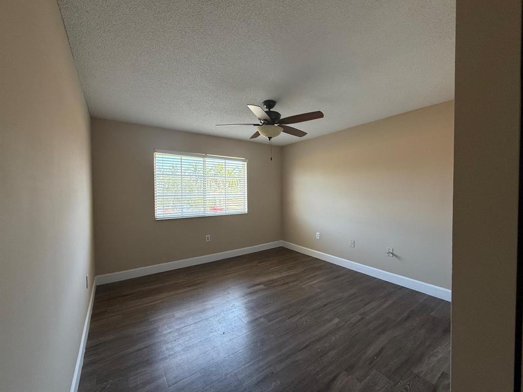 3779 Northwest Mediterranean Lane, Unit 207 Jensen Beach, FL 34957 - Photo 15 of 20 an empty room with wooden floor fan and windows