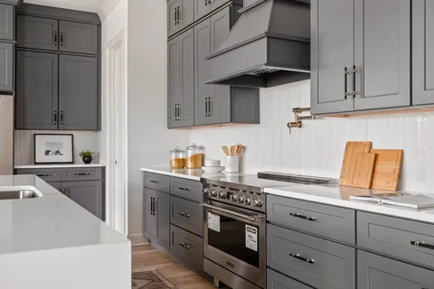 a kitchen with stainless steel appliances granite countertop a stove top oven a sink dishwasher and a refrigerator with wooden floor