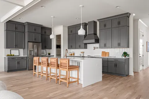 a kitchen with stainless steel appliances kitchen island granite countertop a table chairs stove and cabinets