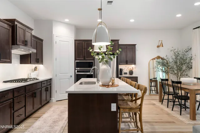 a dining room with kitchen island stainless steel appliances furniture a chandelier and kitchen view