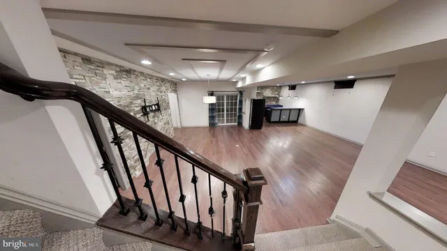a view of an empty room with wooden floor and stairs