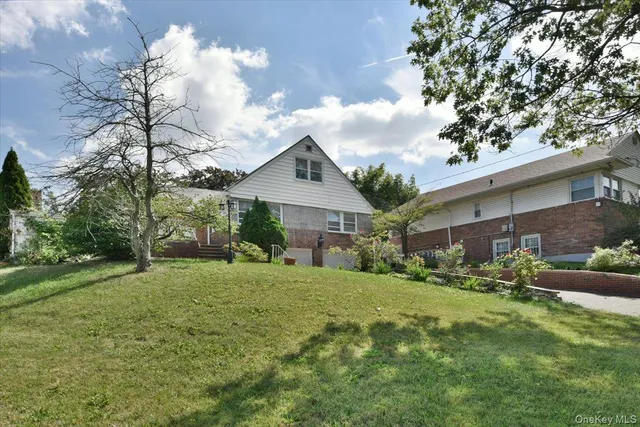 a yellow house sitting in middle of the grass and covered with trees