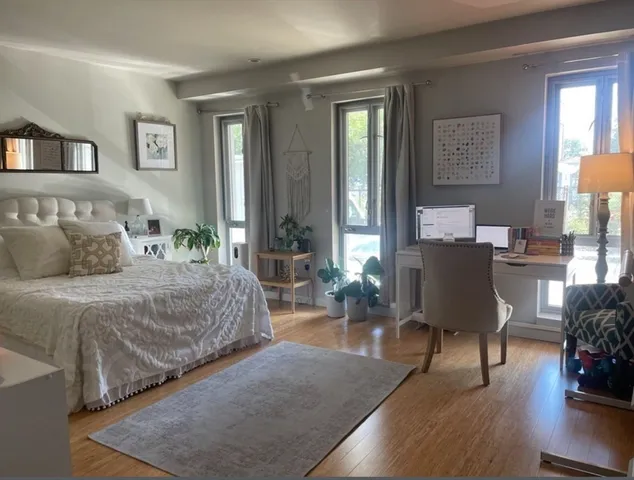 a bedroom with a bed couches chair and three windows