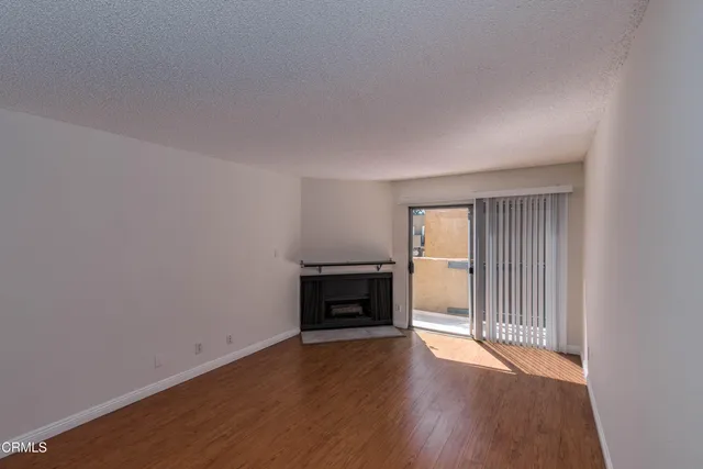 an empty room with wooden floor fireplace and windows