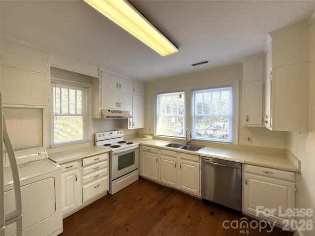 a kitchen with a sink stove cabinets and wooden floor