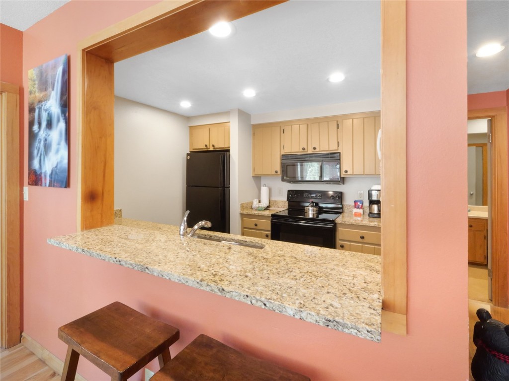 22280 Highway 6, Unit 1717 Keystone, CO 80435 - Photo 7 of 21 a kitchen with kitchen island granite countertop a refrigerator and a stove top oven