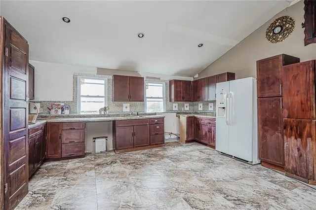 a large kitchen with granite countertop a refrigerator and a stove top oven